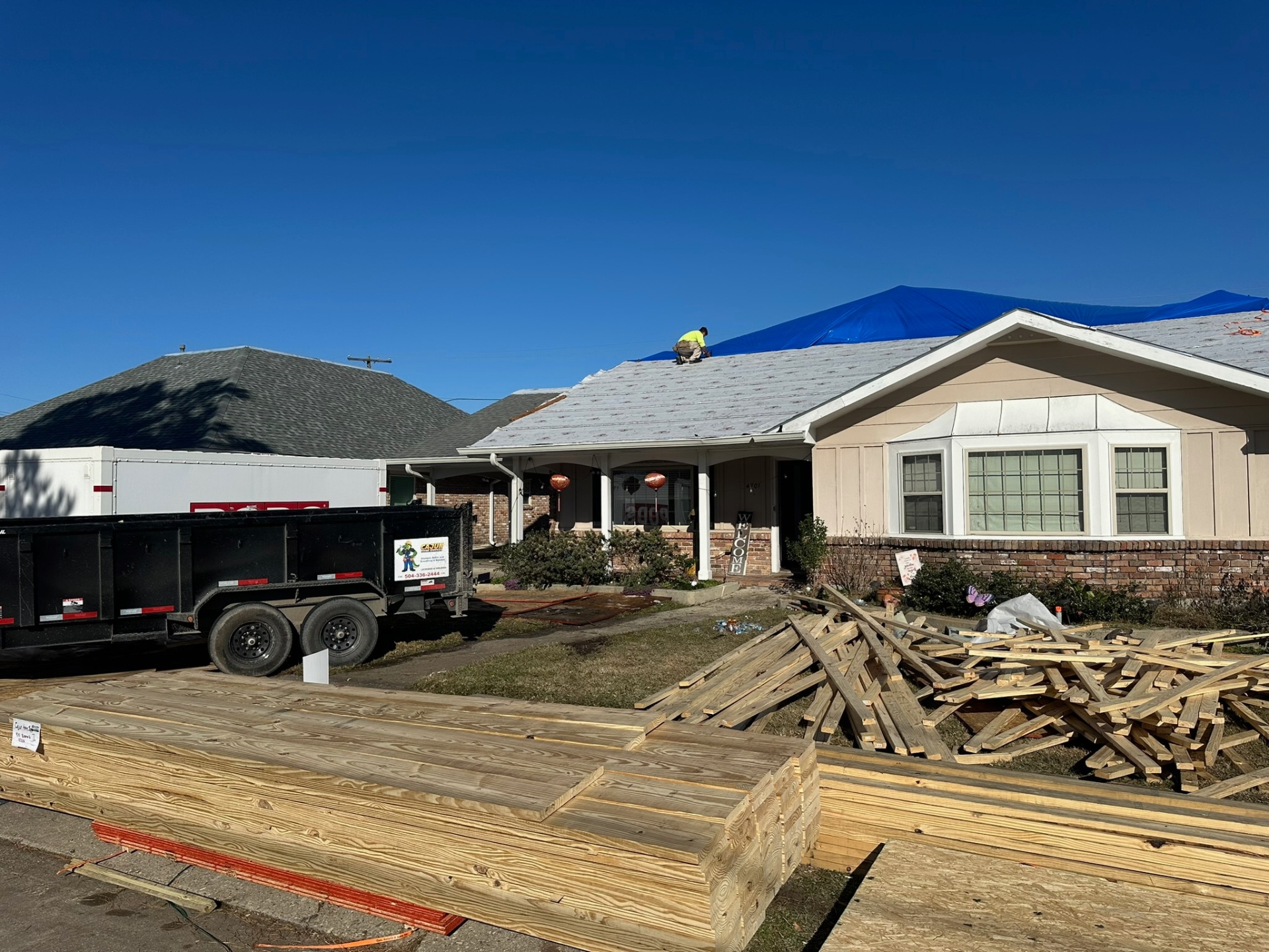 Cajun Home Services crew performing roof replacement with branded trailer on jobsite in Metairie Louisiana
